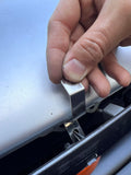 Hand holding a metal bracket on a hood